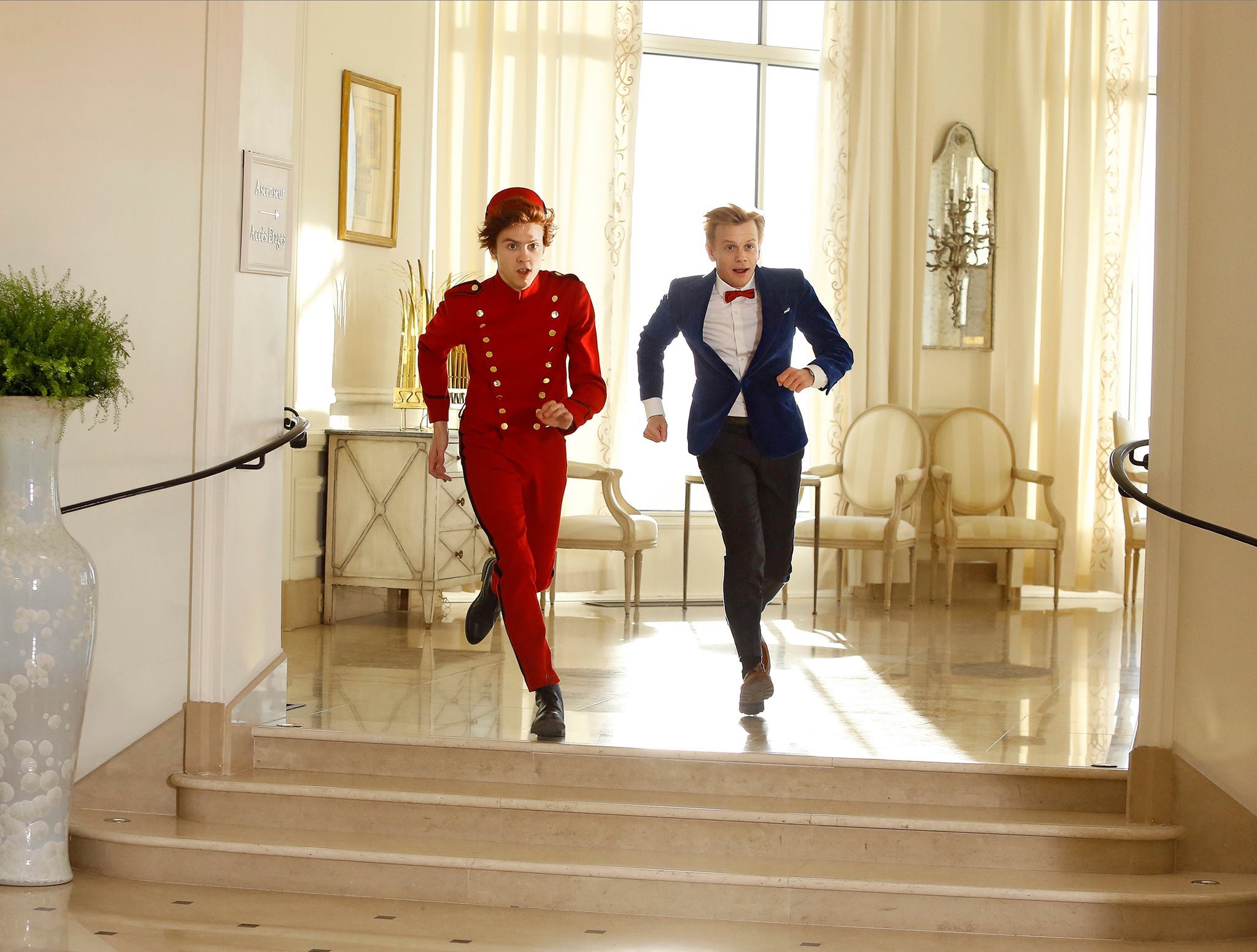 Spirou and Fantasio (Thomas Solivérès and Alex Lutz) running in hotel, from film shoot (image from facebook.com/SpirouEtFantasio.Film/)